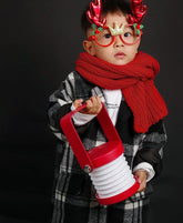 Child holding a red Portable Lantern Lamp USB Rechargeable, wearing festive red accessories.