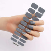 Gel nail stickers in various gray shades on a hand.