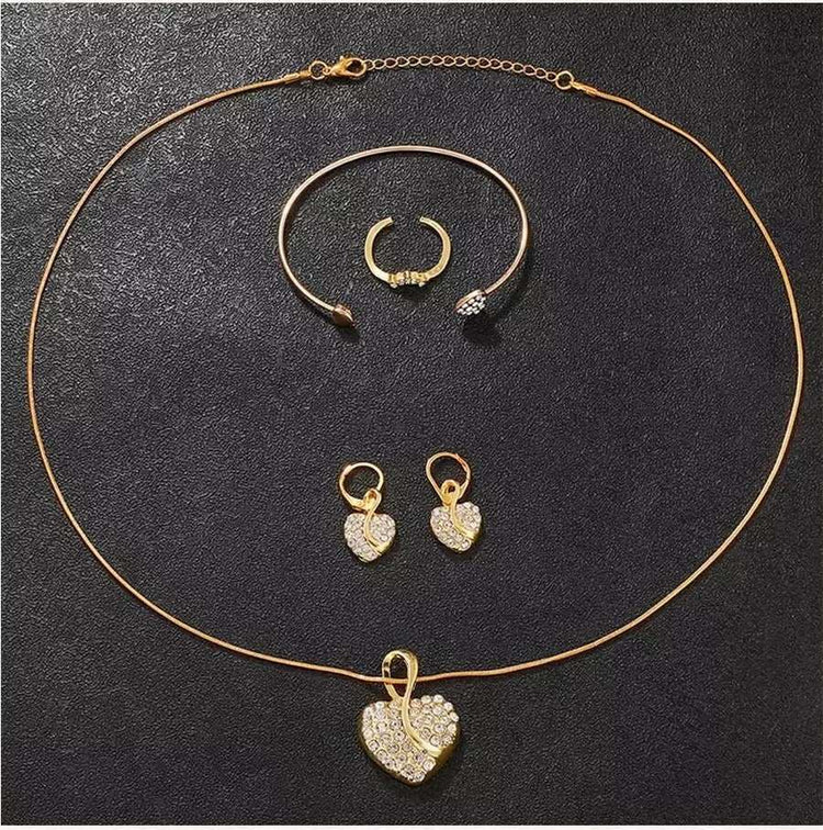 Gold diamond bracelet, ring, earrings, and necklace set with heart design.