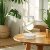 Floating moon table lamp on a wooden table in a sunlit room with plants.