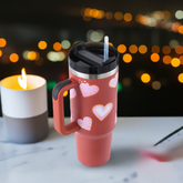 thermos cup with handle and straw on a table with blurred city lights in background