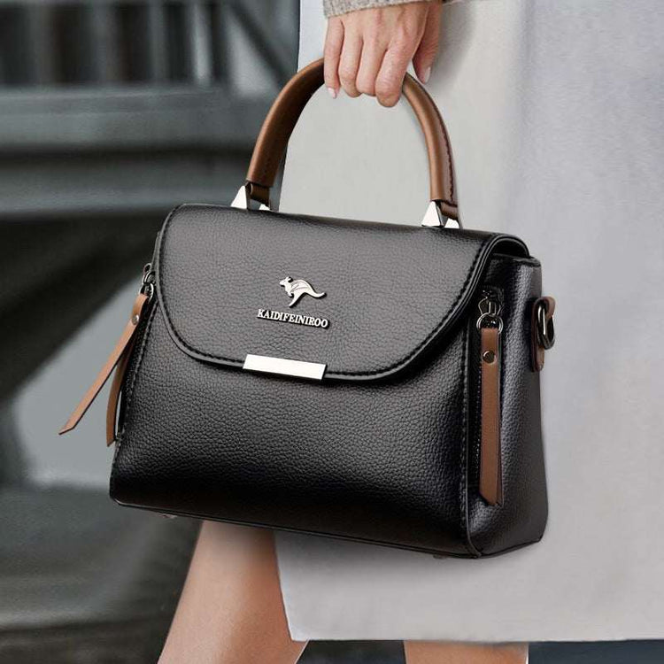 Fashionable women's black leather crossbody shoulder bag with brown handle, chic design.