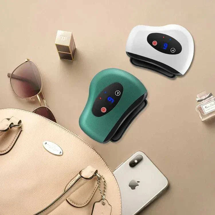 Gua Sha Électrique devices on a table with sunglasses, perfume, a beige handbag, and a smartphone.