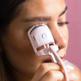 woman using heated eyelash curler on eyelashes