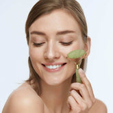 Woman using Jade Roller for facial massage and skincare routine.