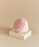 Pink revitalizing scalp massager with ergonomic design and soft silicone bristles on display.